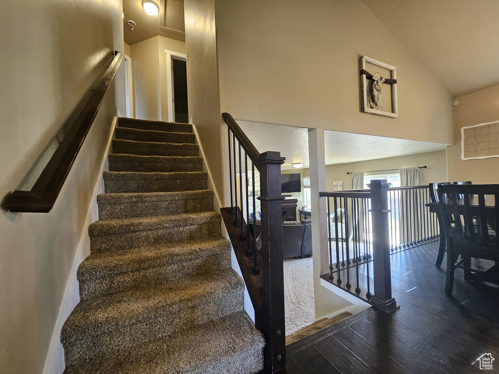 Stairway with vaulted ceiling and hardwood / wood-style flooring