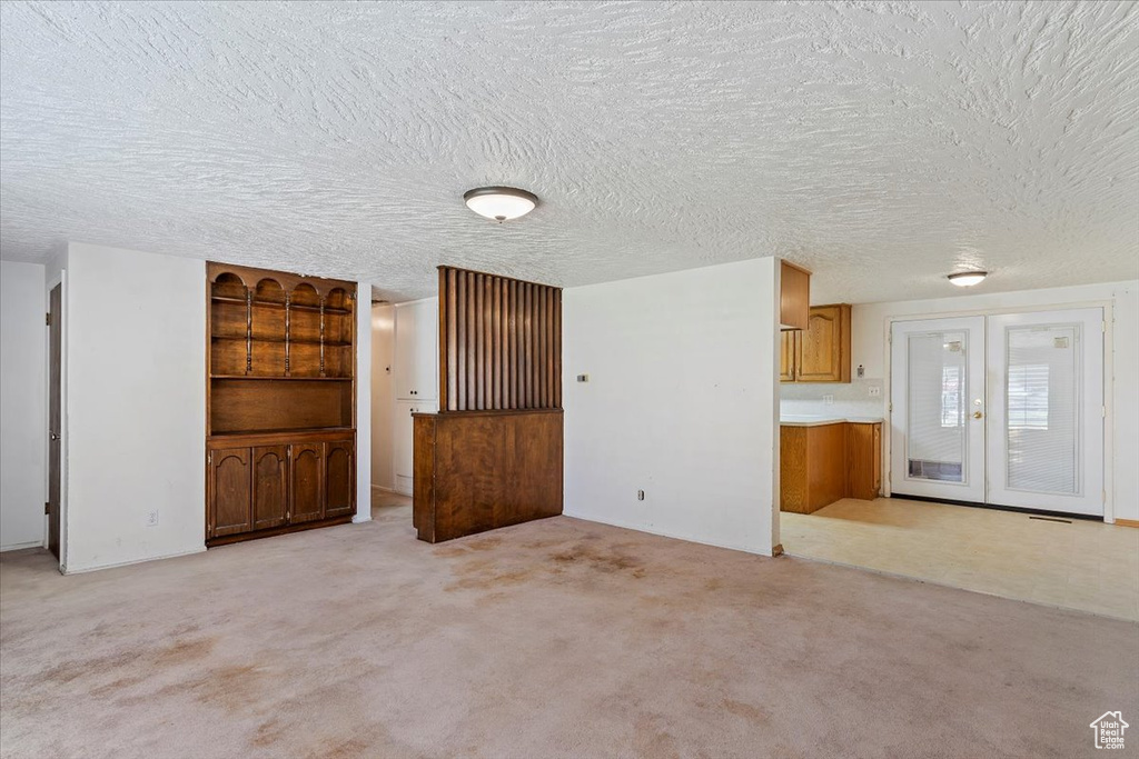Unfurnished living room with light carpet and french doors