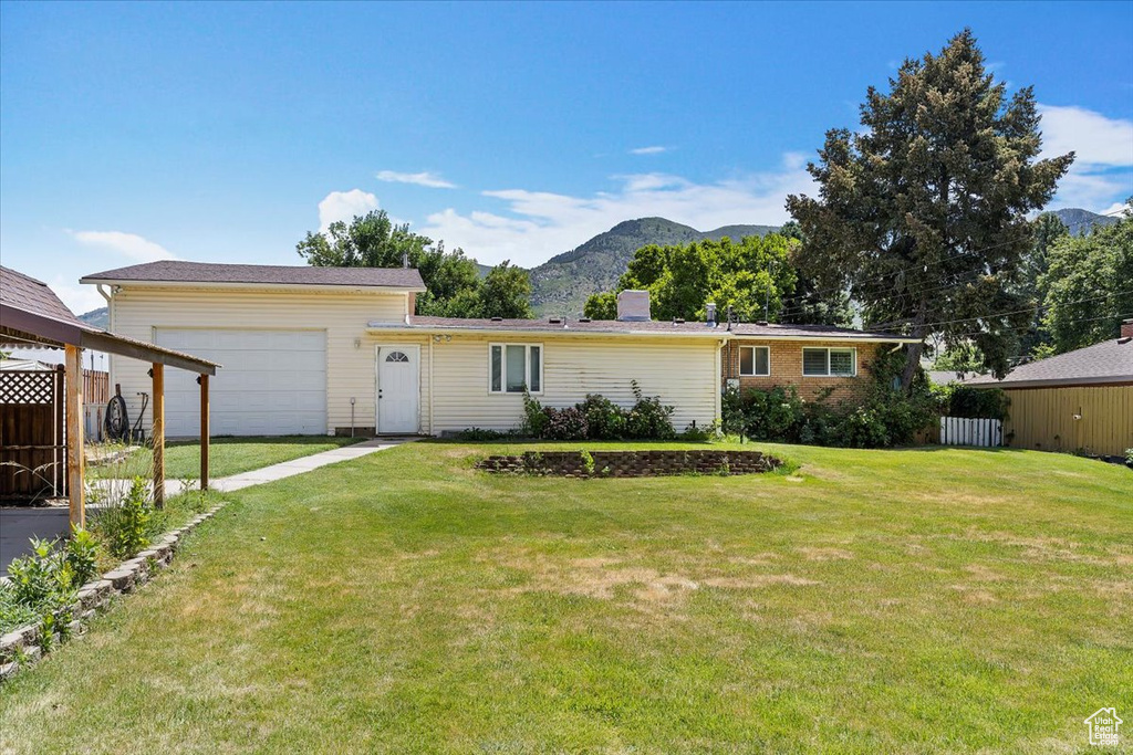 Ranch-style home with an attached garage, a mountain view, driveway, and a chimney