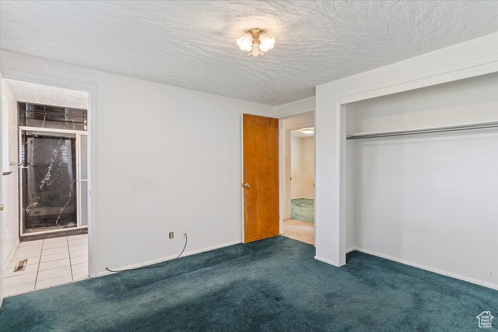 Unfurnished bedroom with carpet flooring, a closet, ensuite bath, and a textured ceiling