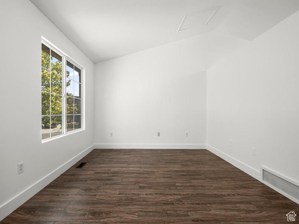 Unfurnished room featuring vaulted ceiling and dark wood-style floors