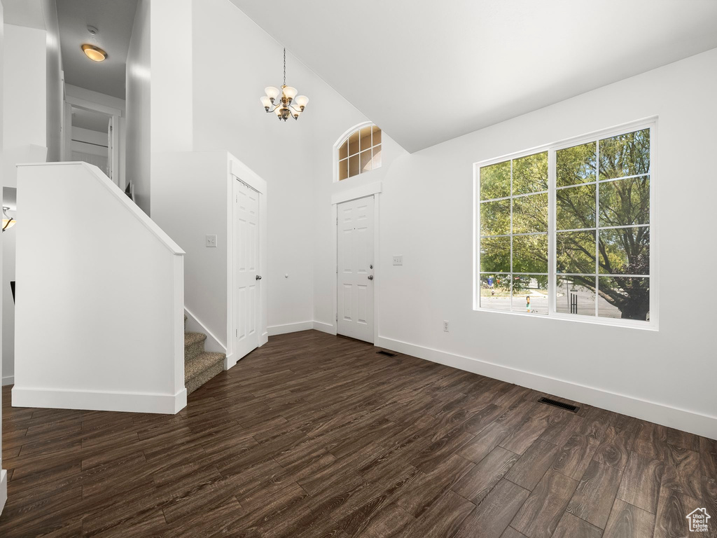 Entrance foyer featuring a chandelier, stairs, dark wood-style floors, and high vaulted ceiling