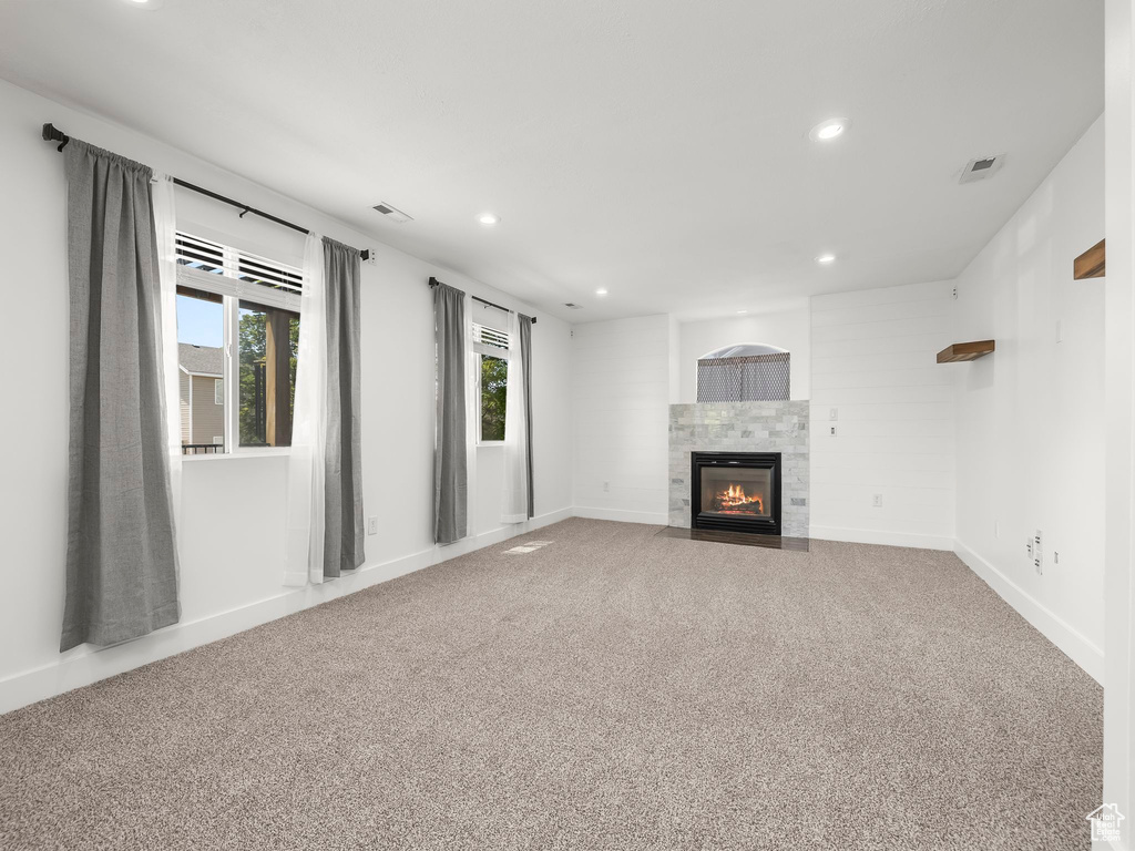 Unfurnished living room featuring plenty of natural light, recessed lighting, carpet floors, and a tiled fireplace