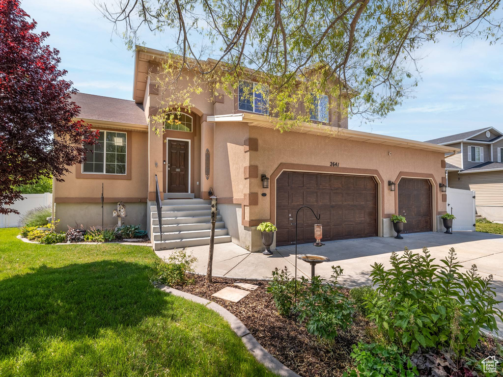 Traditional-style house with a front yard, stucco siding, and driveway