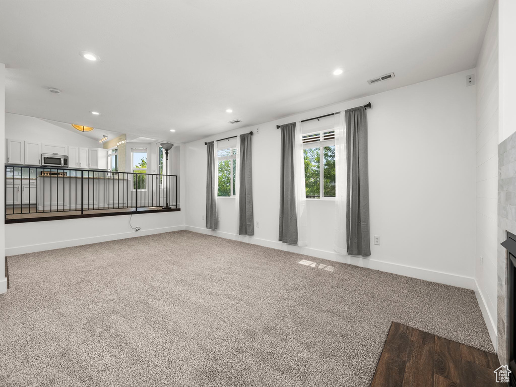 Unfurnished room featuring recessed lighting, carpet, a fireplace, and vaulted ceiling
