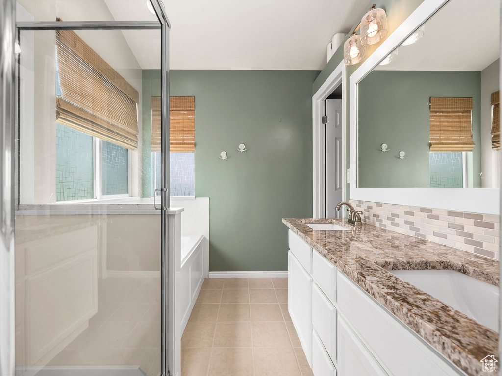 Full bath featuring double vanity, a shower stall, a bath, and tile patterned flooring