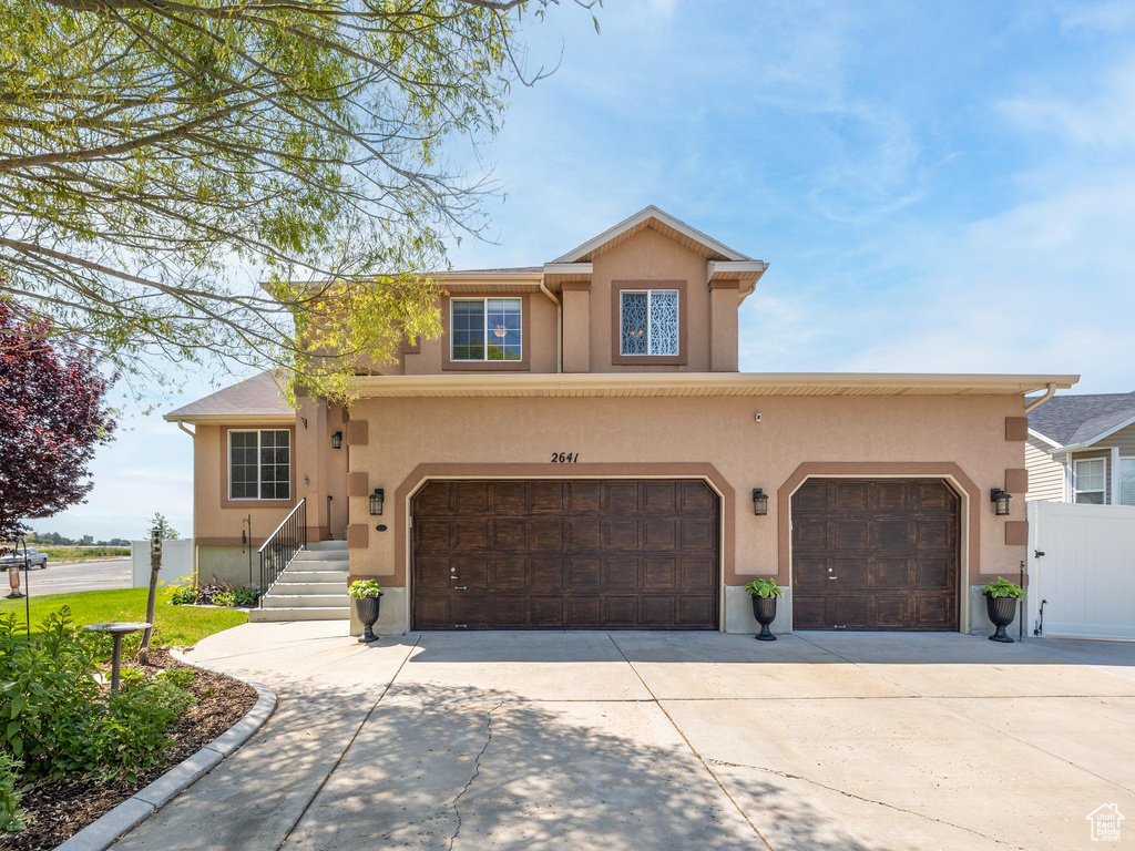 Traditional-style house with stucco siding, driveway, and a garage