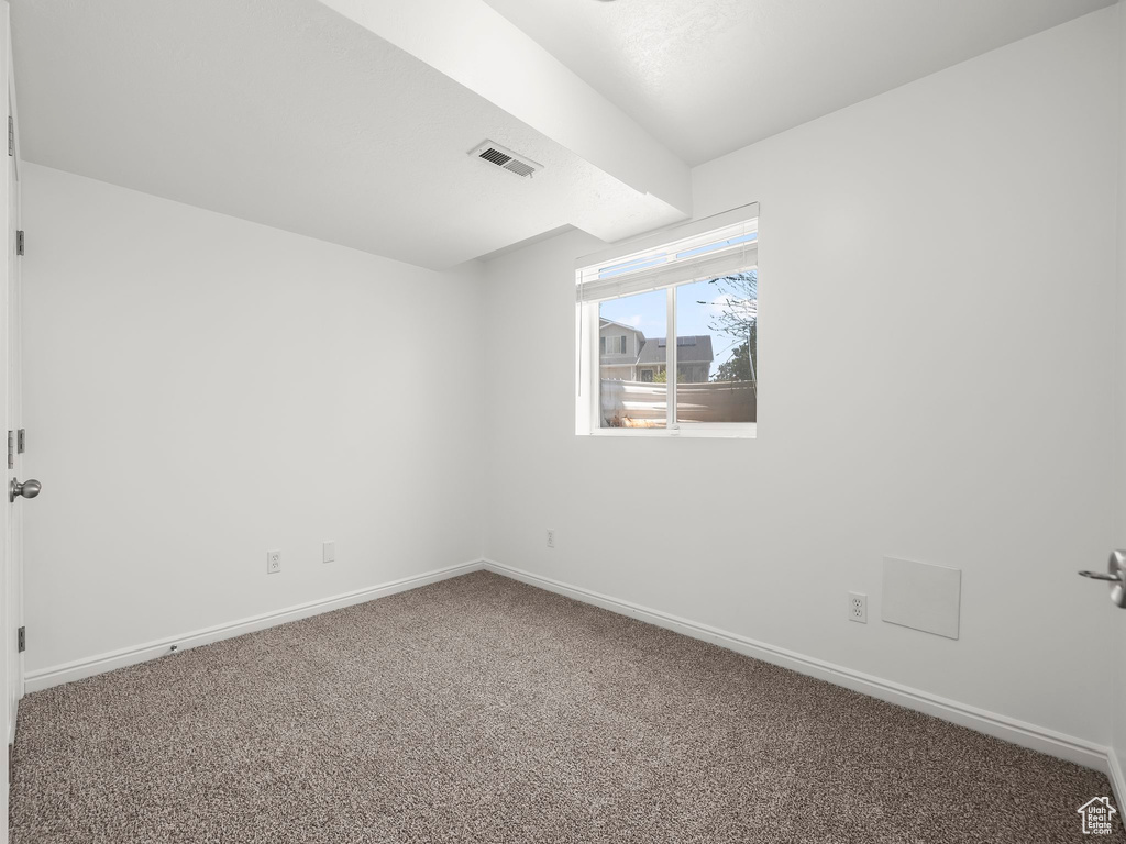 Carpeted spare room featuring baseboards