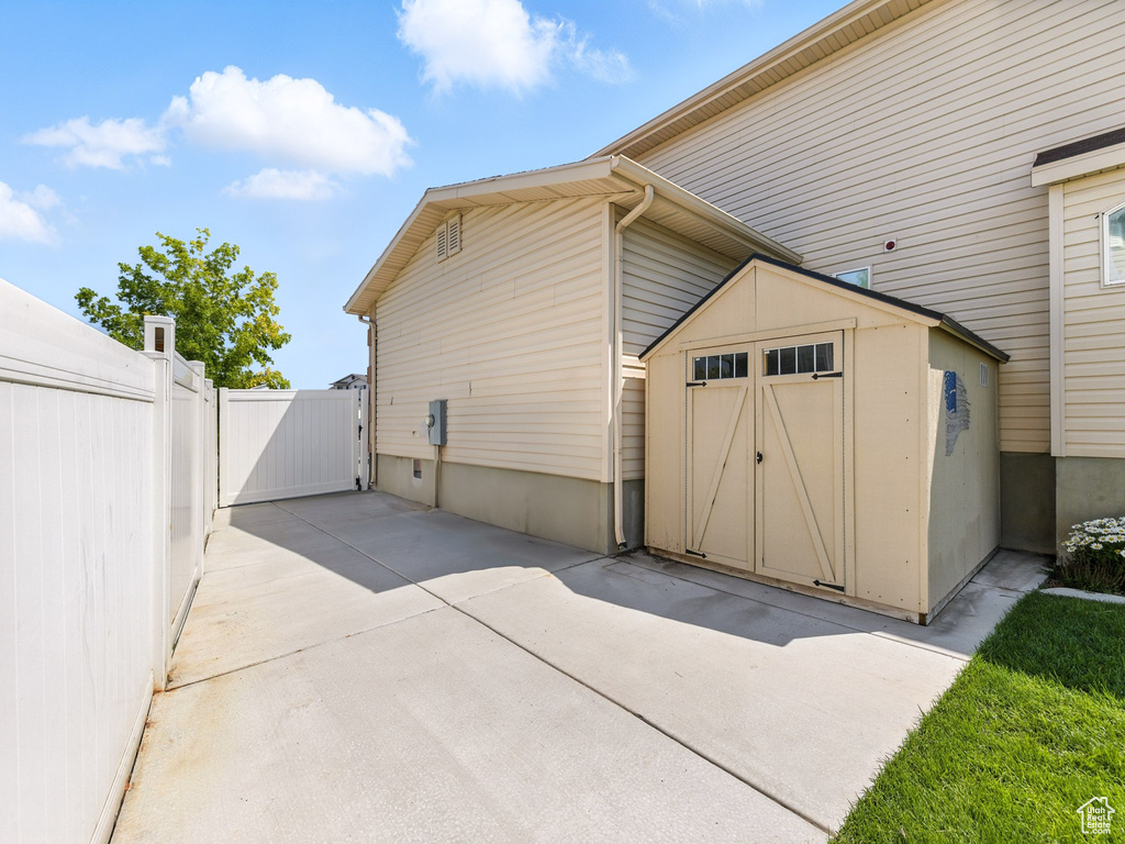 View of side of property with a shed, a gate, and a patio