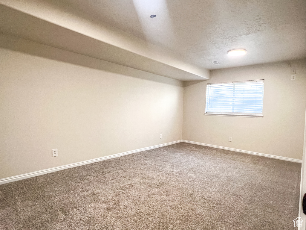 Carpeted empty room with baseboards and a textured ceiling