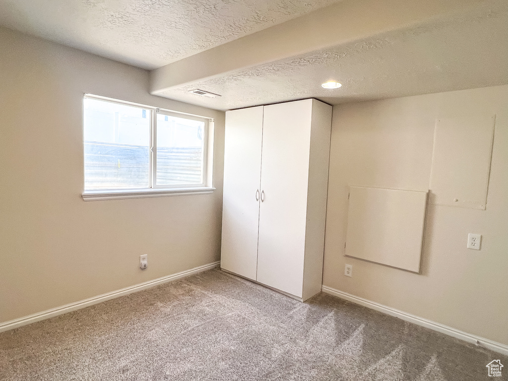 Unfurnished bedroom with a textured ceiling, carpet, and a closet