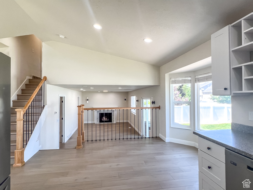 Kitchen featuring stainless steel dishwasher, open shelves, light wood finished floors, white cabinetry, and recessed lighting
