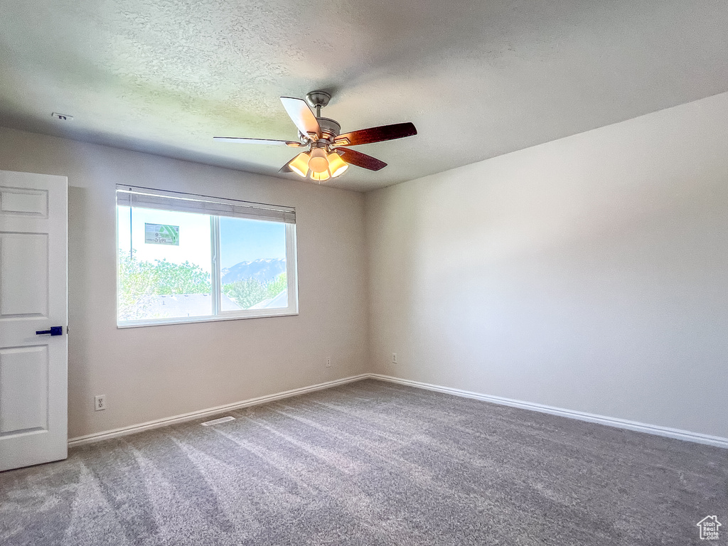 Spare room featuring ceiling fan, carpet flooring, and a textured ceiling