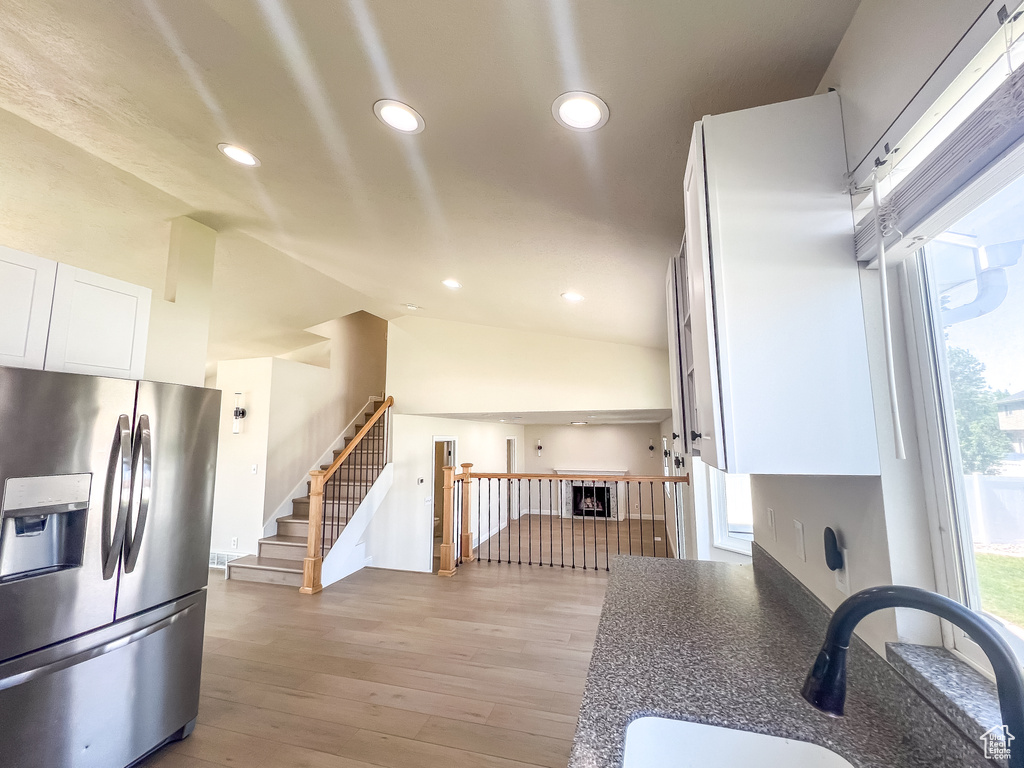 Kitchen with stainless steel fridge, white cabinetry, recessed lighting, light wood-style flooring, and dark countertops
