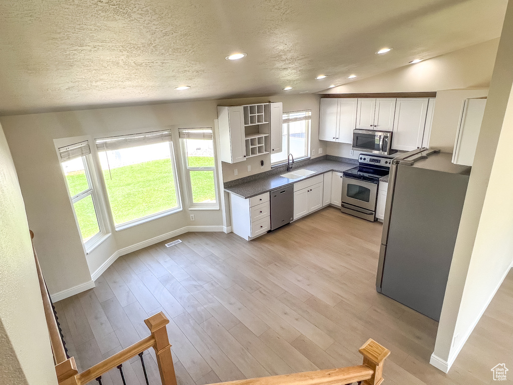 Kitchen with appliances with stainless steel finishes, dark countertops, open shelves, white cabinetry, and recessed lighting