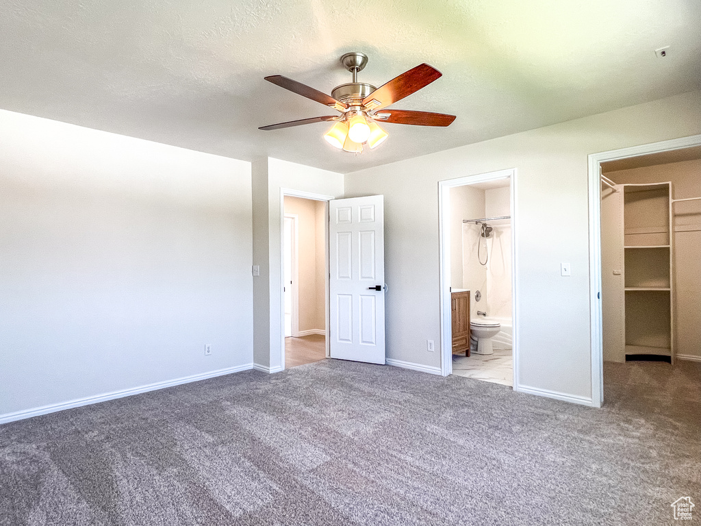Unfurnished bedroom with carpet floors, a walk in closet, ensuite bath, a ceiling fan, and a closet