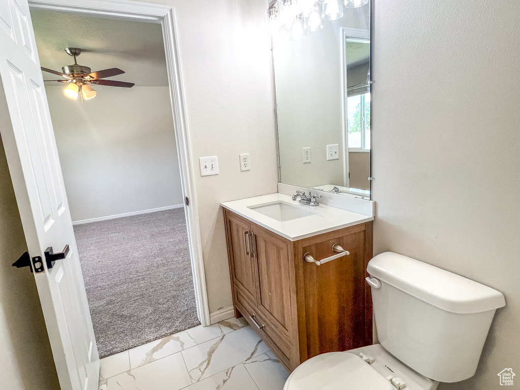 Bathroom with marble look tile flooring, vanity, and a ceiling fan
