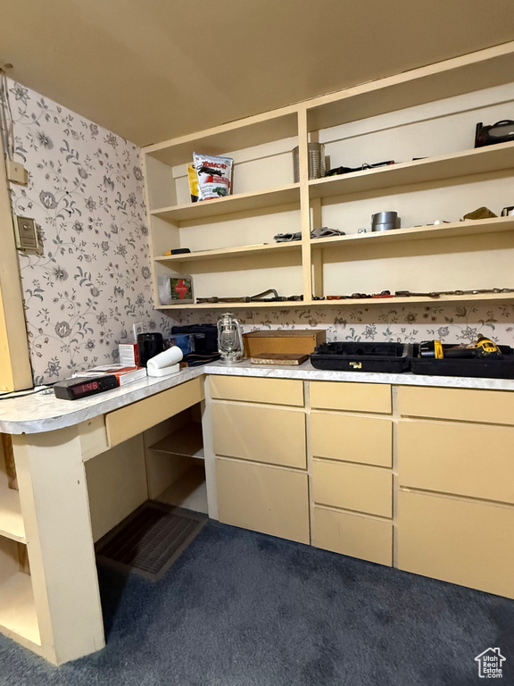 Kitchen featuring open shelves, wallpapered walls, light countertops, and dark carpet