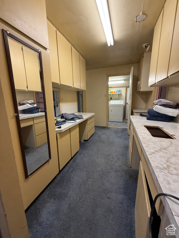 Kitchen featuring light countertops, dark colored carpet, separate washer and dryer, and cream cabinetry