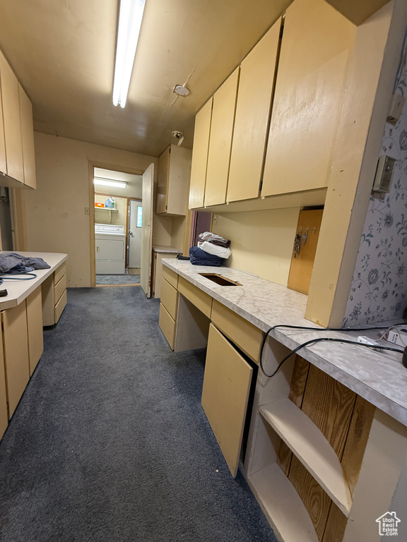 Kitchen with washer / clothes dryer, light countertops, carpet flooring, and built in desk