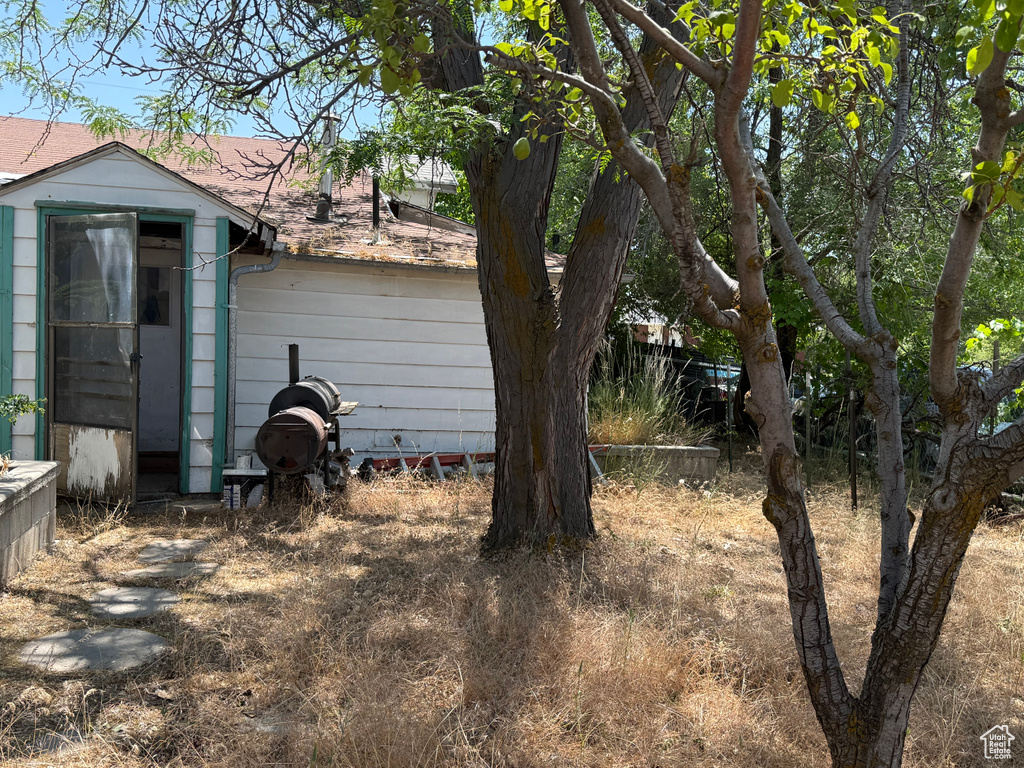View of side of home with an outdoor structure and a shingled roof