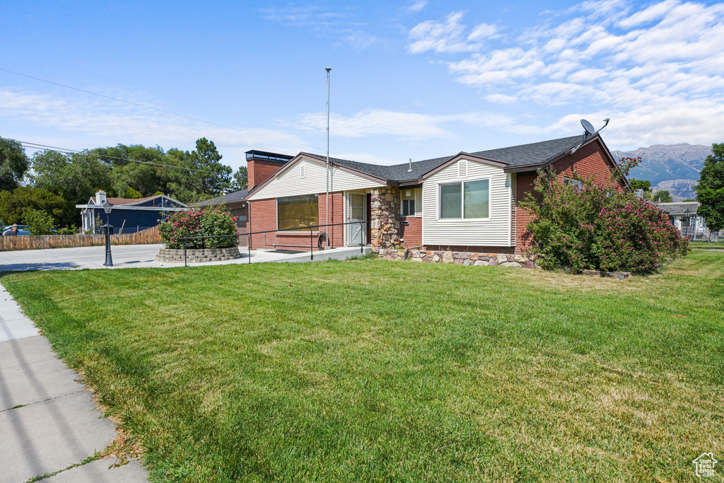 Ranch-style house with a front yard, brick siding, and a chimney