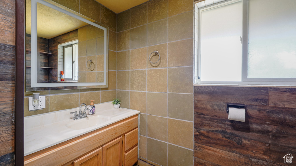 Bathroom featuring vanity, tile walls, and tasteful backsplash
