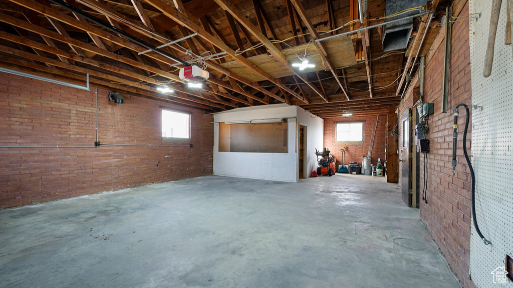 Basement featuring a garage, healthy amount of natural light, and brick wall