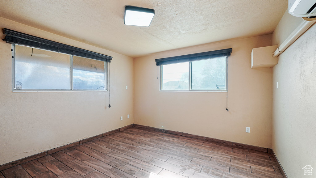 Empty room featuring wood finished floors and a wall mounted AC