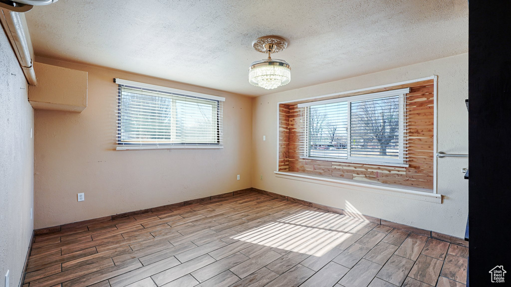 Unfurnished room featuring a textured ceiling, wood finished floors, and a chandelier