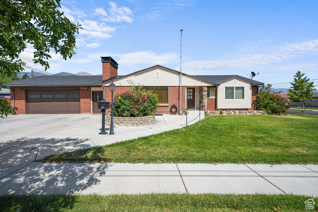 Ranch-style home featuring concrete driveway, a garage, a front lawn, and brick siding