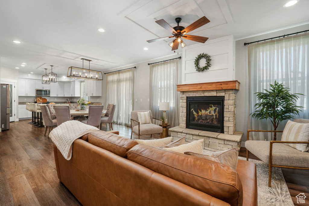 Living area with healthy amount of natural light, a stone fireplace, recessed lighting, and dark wood-type flooring