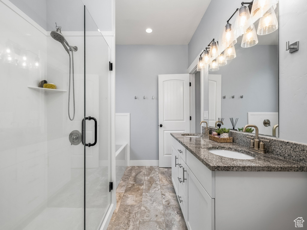 Full bath featuring a stall shower, double vanity, a bath, and marble finish flooring