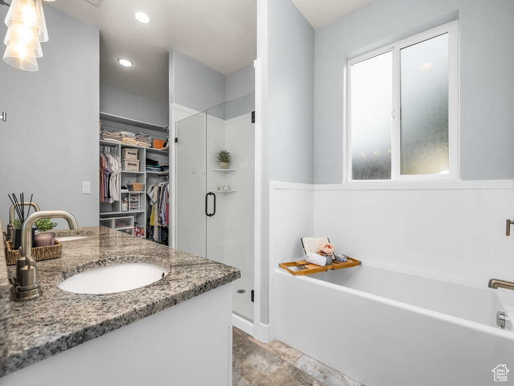 Full bath featuring a spacious closet, a shower stall, a bath, double vanity, and recessed lighting