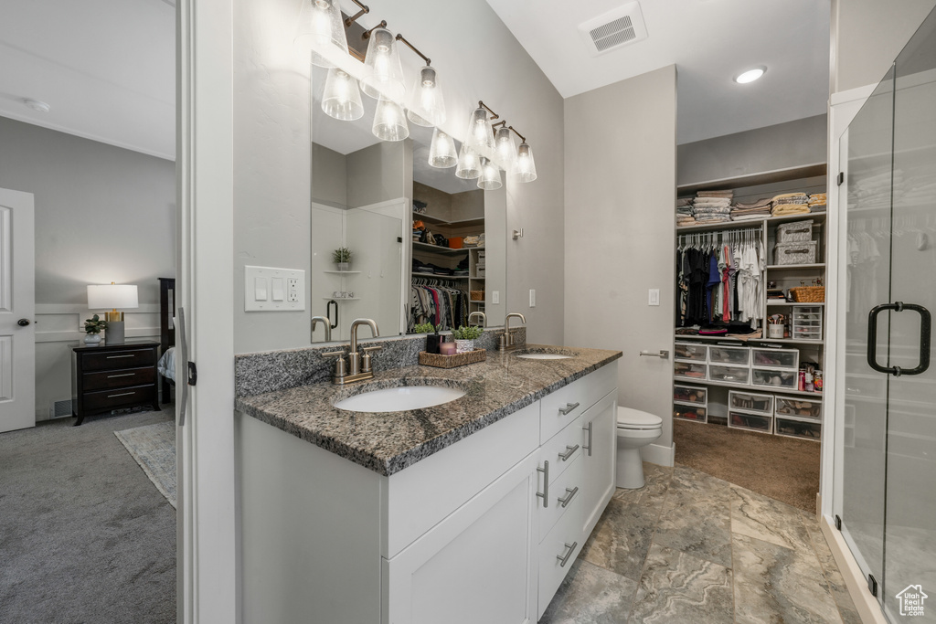 Full bath with a spacious closet, double vanity, and a shower stall