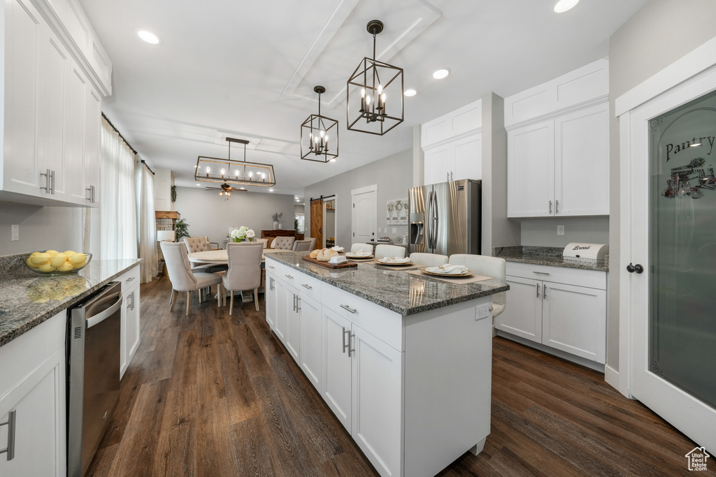 Kitchen with stainless steel appliances, a center island, a chandelier, white cabinetry, and recessed lighting