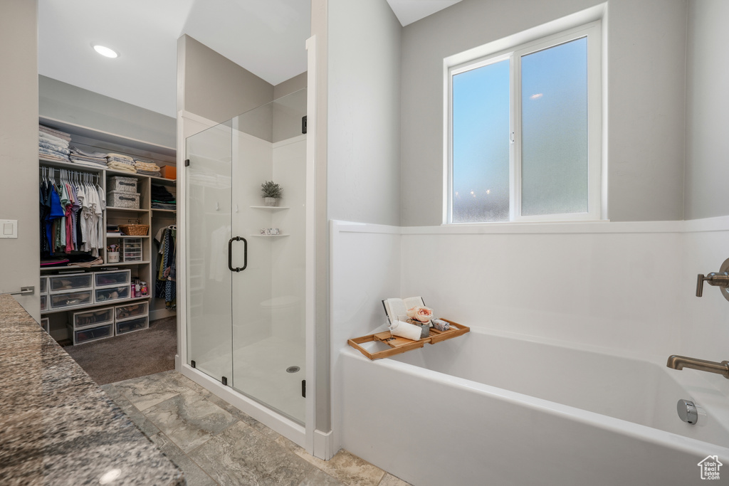 Bathroom featuring a bath, a shower stall, and a spacious closet