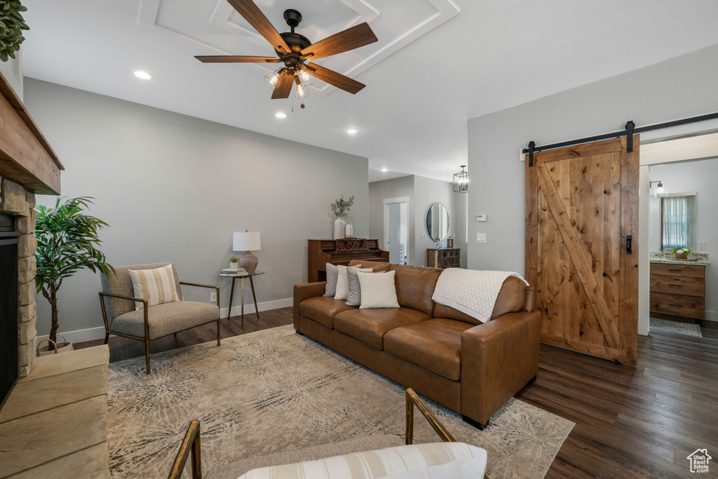 Living room with ceiling fan, a barn door, wood finished floors, and recessed lighting