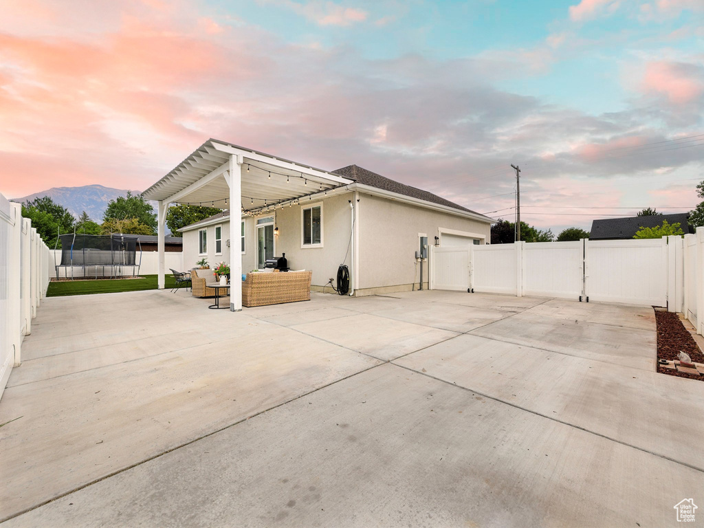 Back of property at dusk with an outdoor living space, a patio, stucco siding, and a fenced backyard