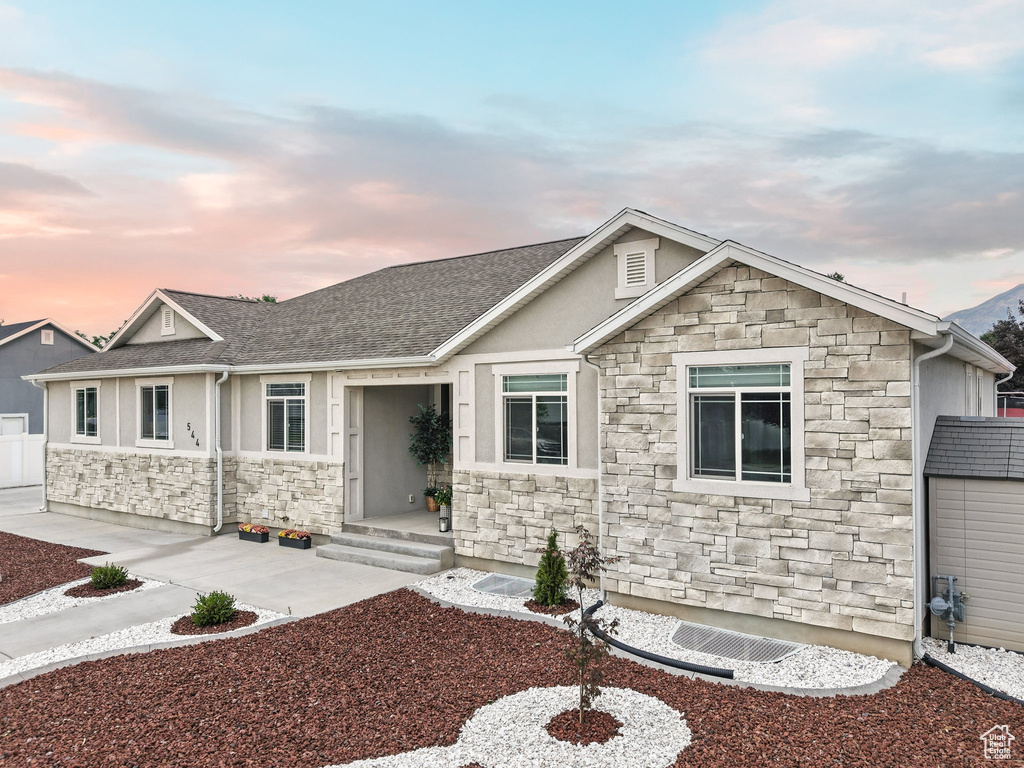 View of front facade featuring stone siding, stucco siding, and a shingled roof