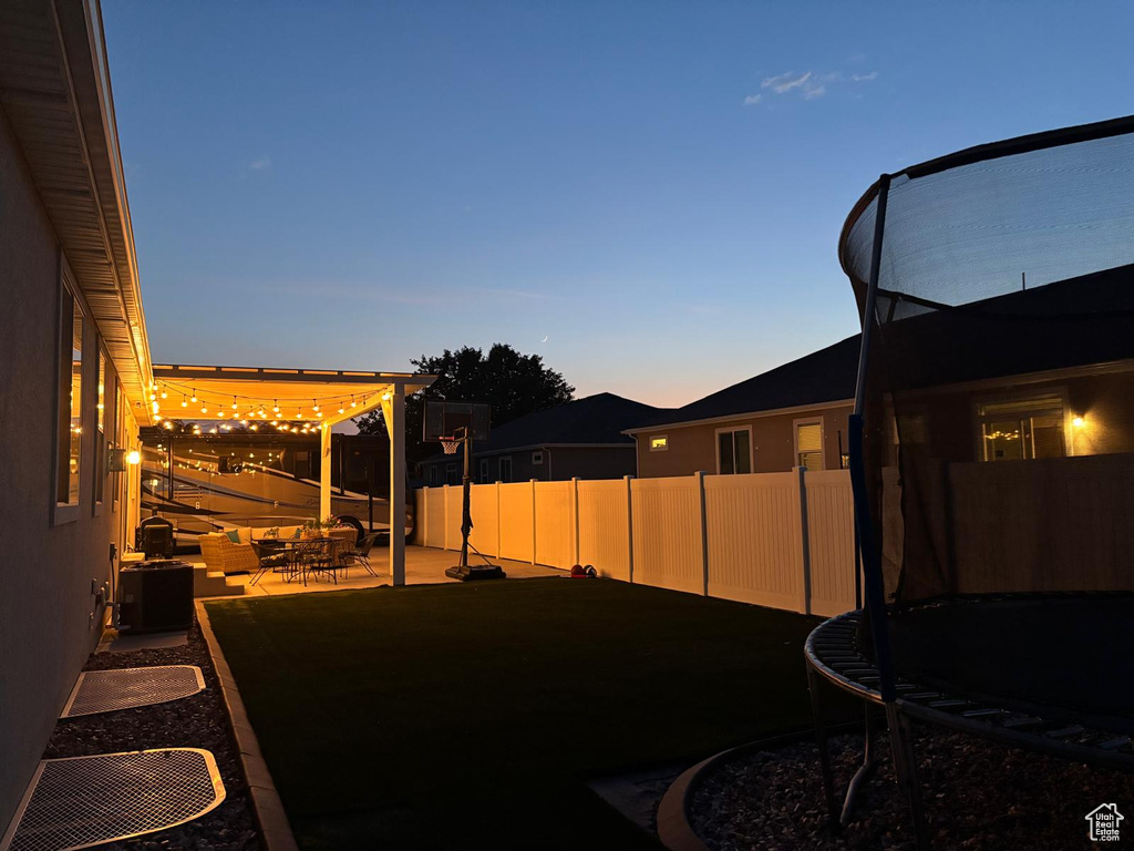 Yard at dusk with a trampoline and a patio