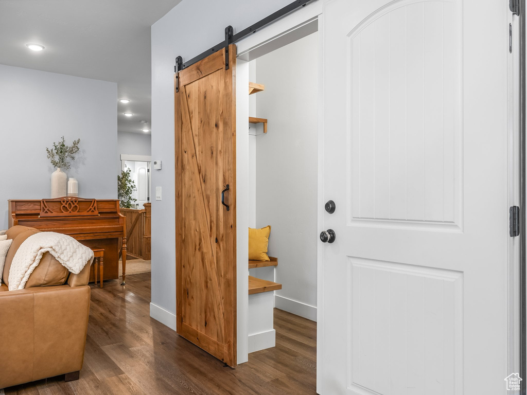 Corridor featuring a barn door, wood finished floors, and recessed lighting
