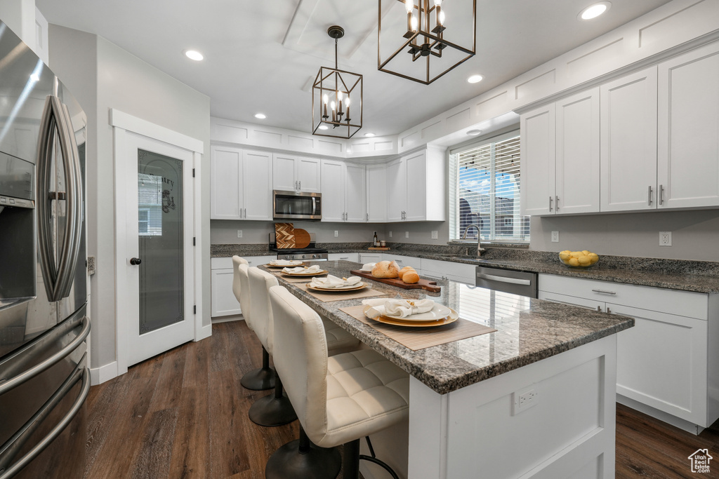 Kitchen with stainless steel appliances, a chandelier, recessed lighting, dark wood finished floors, and white cabinetry