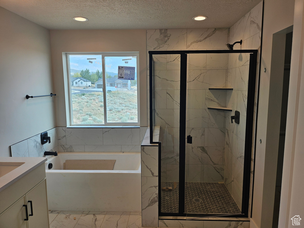 Bathroom featuring marble finish floors, a garden tub, a textured ceiling, vanity, and a marble finish shower