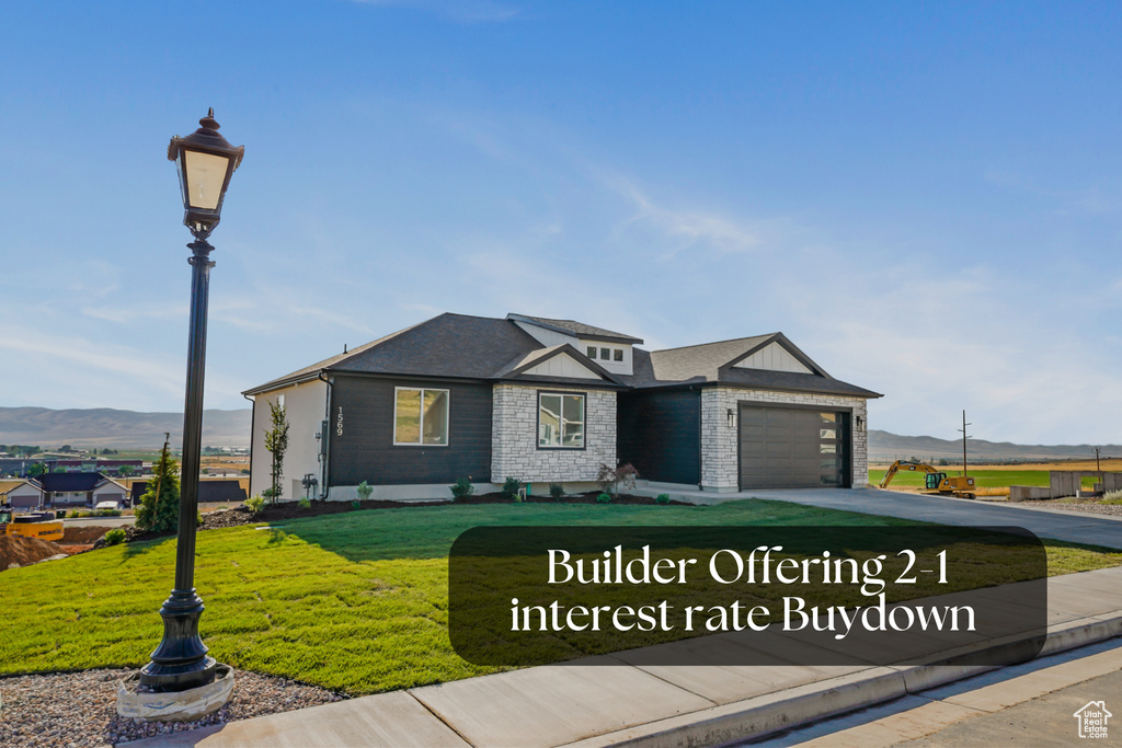 View of front of house with concrete driveway, an attached garage, a front yard, and a mountain view