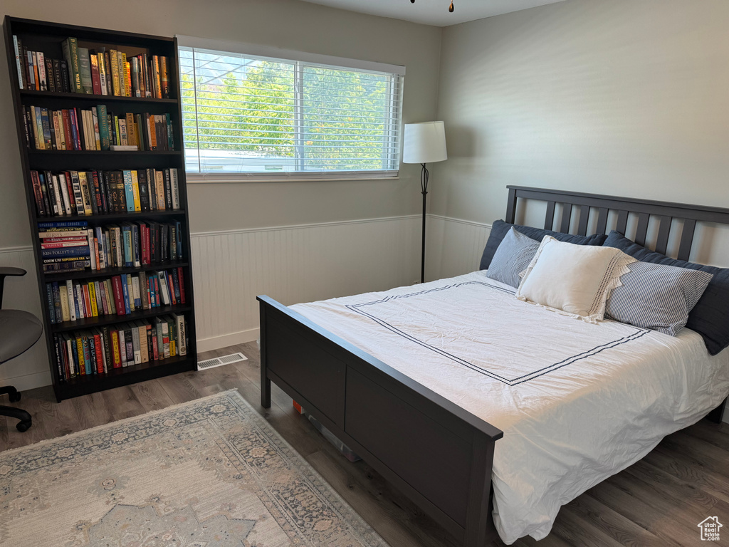 Bedroom with a wainscoted wall and wood finished floors