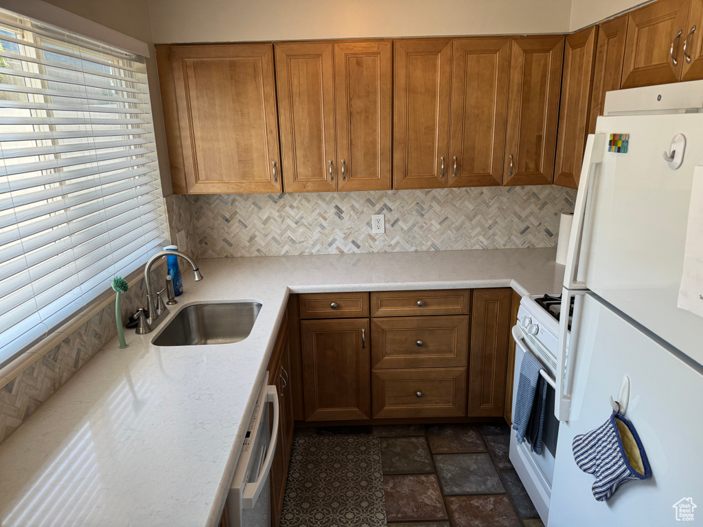 Kitchen featuring white appliances, backsplash, and brown cabinetry