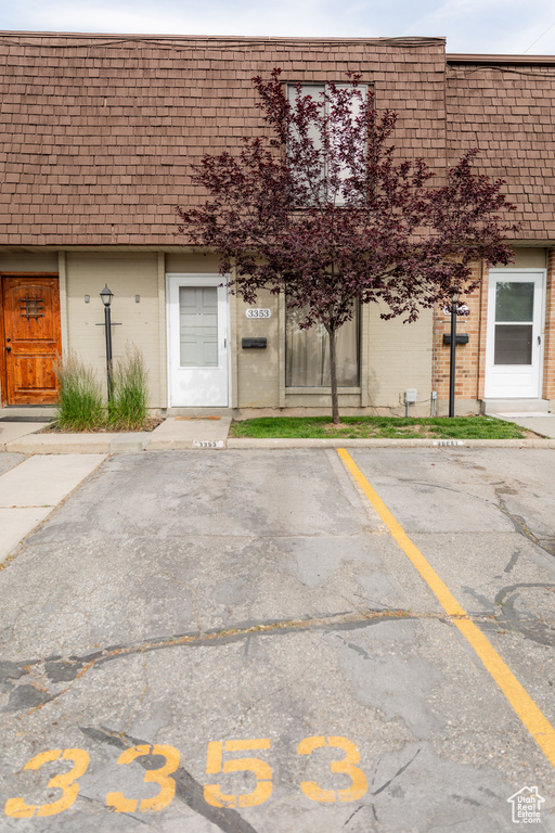 Exterior space featuring mansard roof, brick siding, and uncovered parking