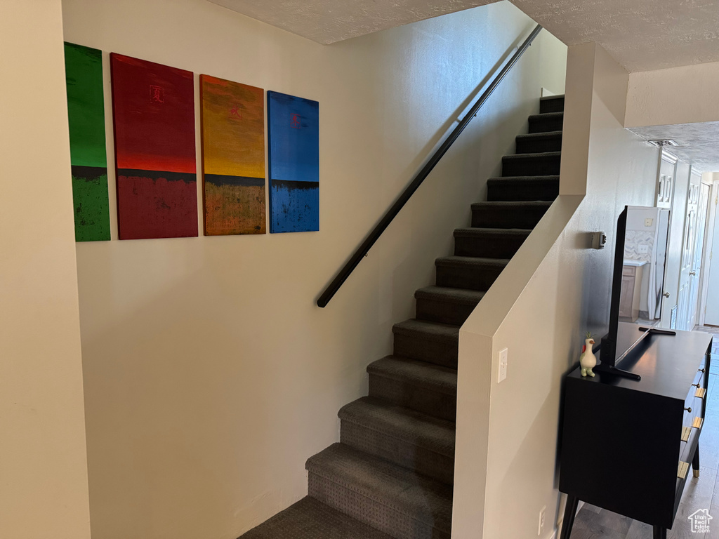Stairway featuring a textured ceiling