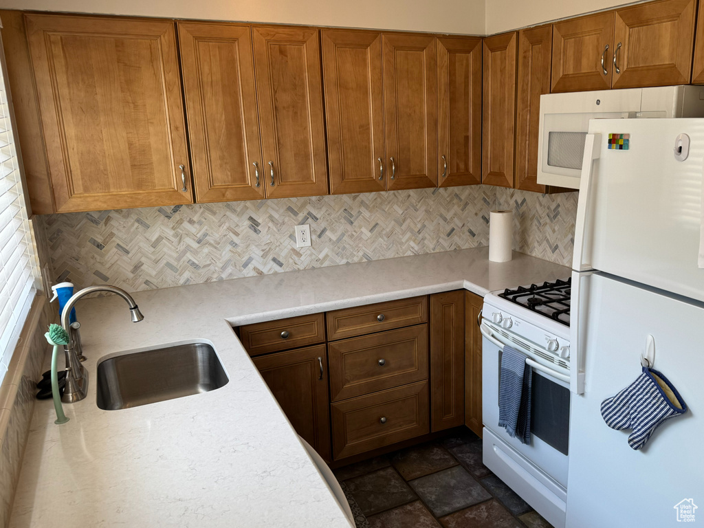Kitchen with white appliances, brown cabinets, and backsplash